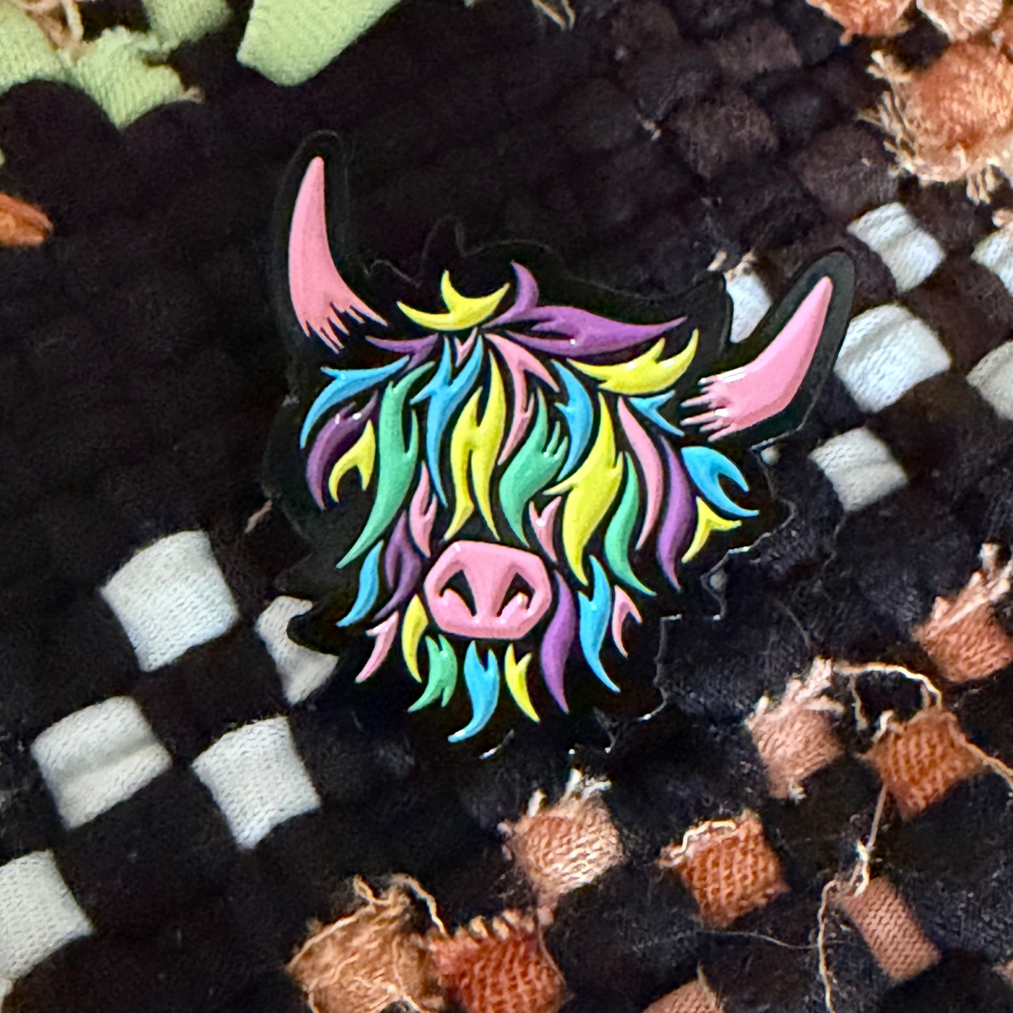 Colorful cow head pin on a textured fabric background