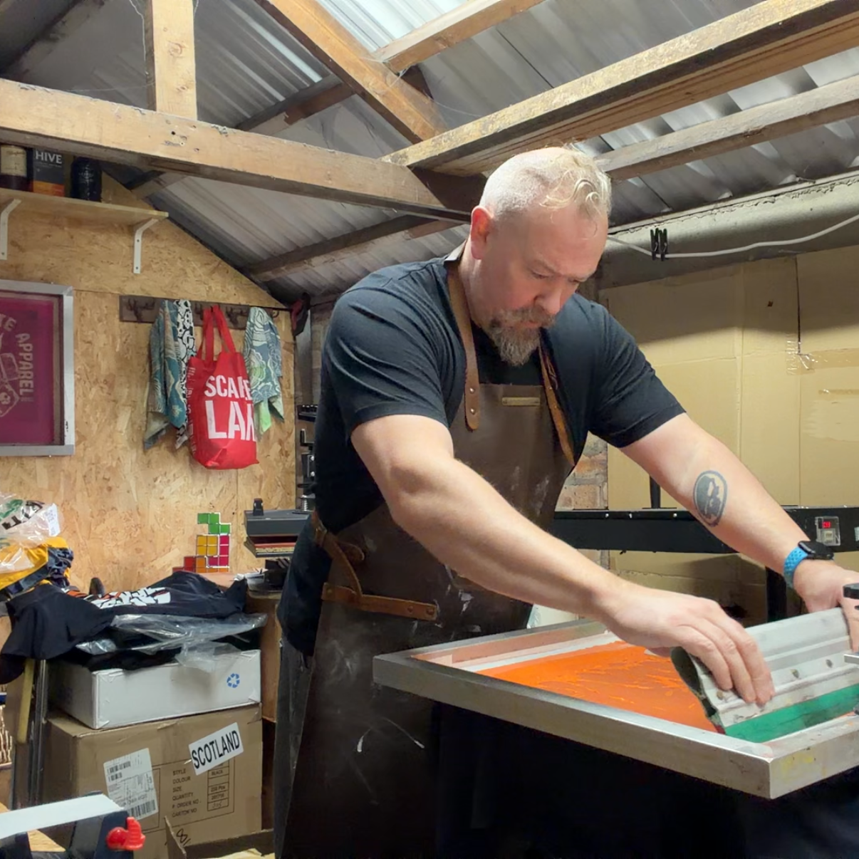Man working with a screen printing press in a workshop.